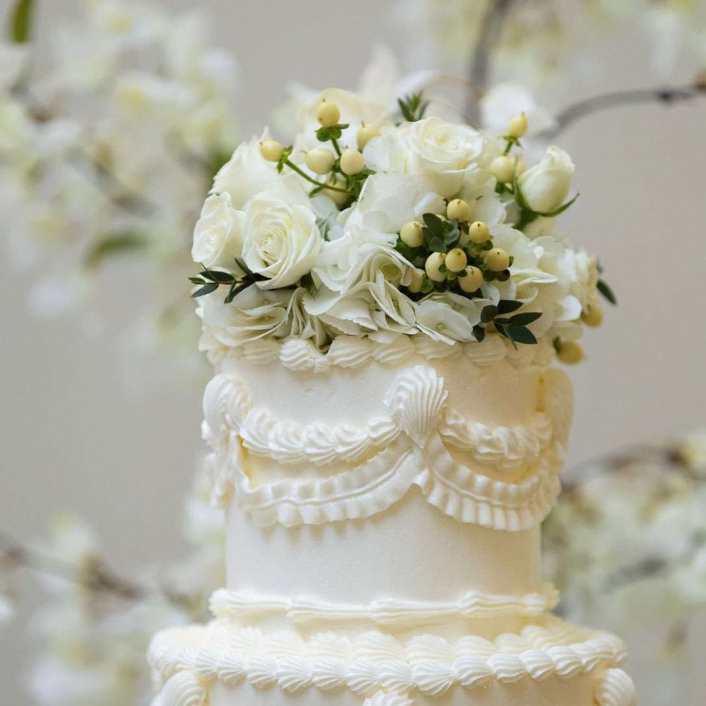 The top of a white wedding cake with white flowers