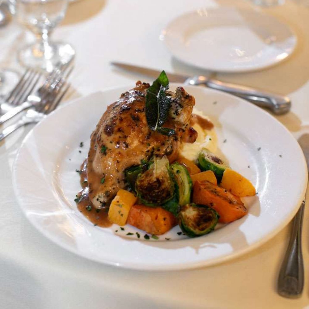 Chicken dish with mashed potatoes and brussel sprouts and carrots.