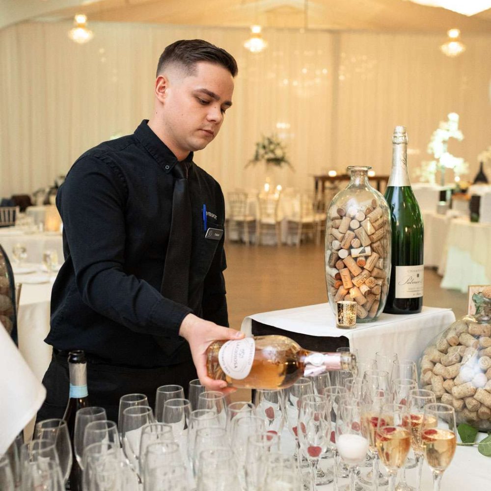 A Danversport employee pours a bottle of sparkling rosé.